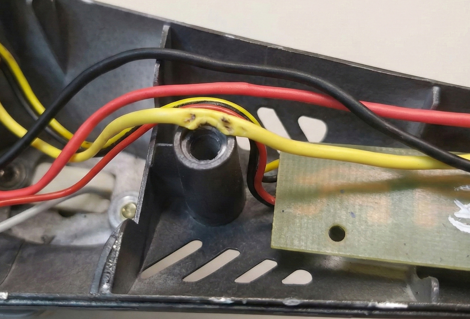 A closeup of a wire pinched between two plastic housing halves, showing exposed copper.